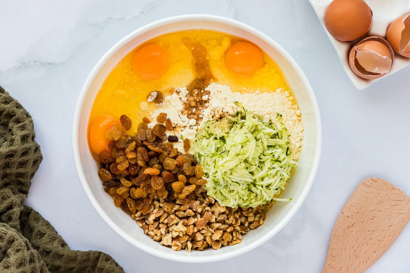 all ingredients for zucchini muffins in a mixing bowl