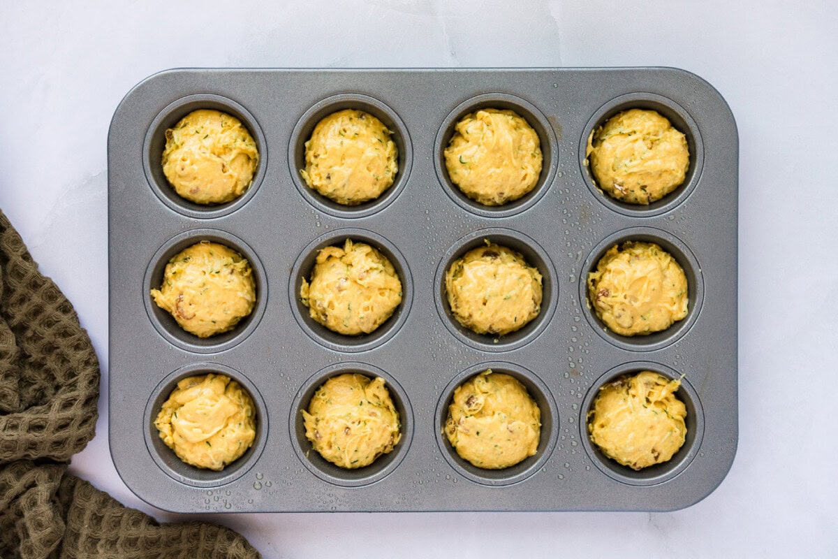 muffin pan filled with zucchini muffin batter