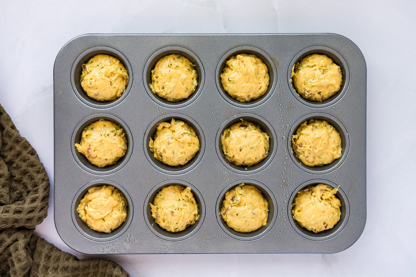 muffin pan filled with zucchini muffin batter