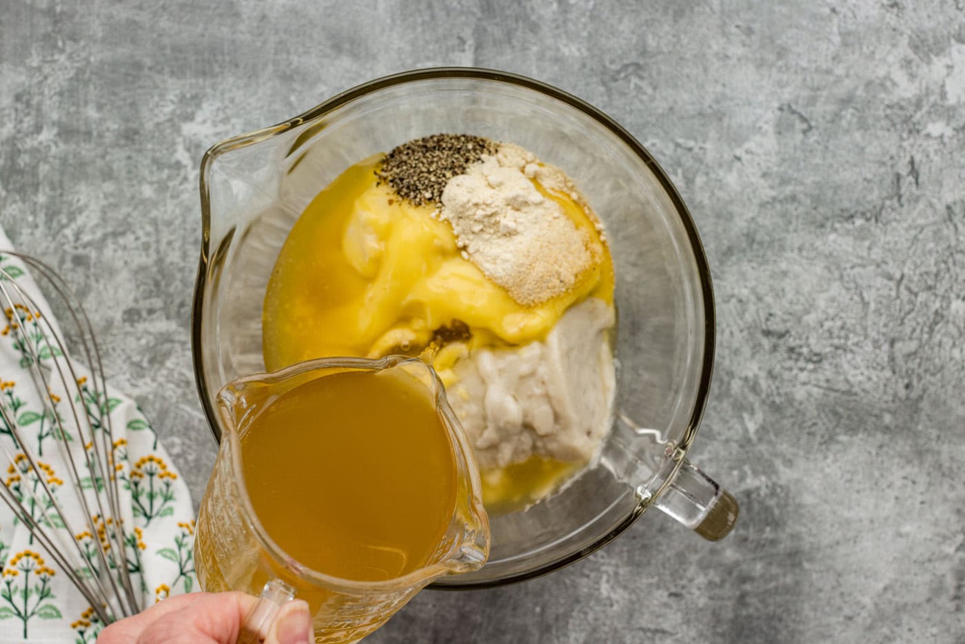 pouring chicken broth into mixing bowl of seasonings and cream of chicken and mushroom soup