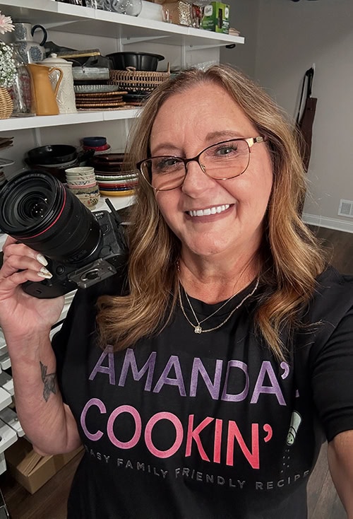 Photo of Amanda Davis, the founder of Amanda's Cookin' in her kitchen studio holding her camera