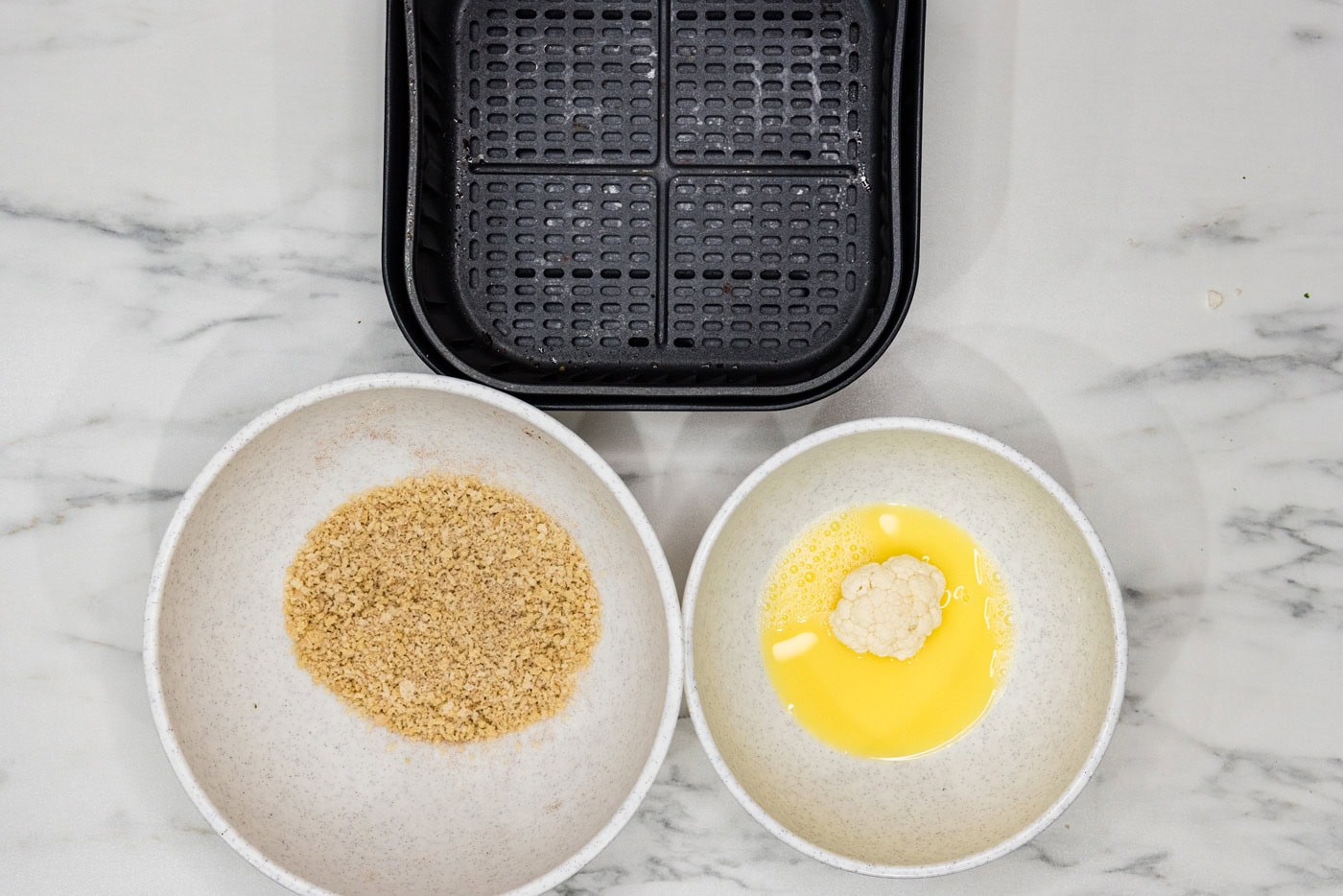 cauliflower florets in a bowl of egg and water
