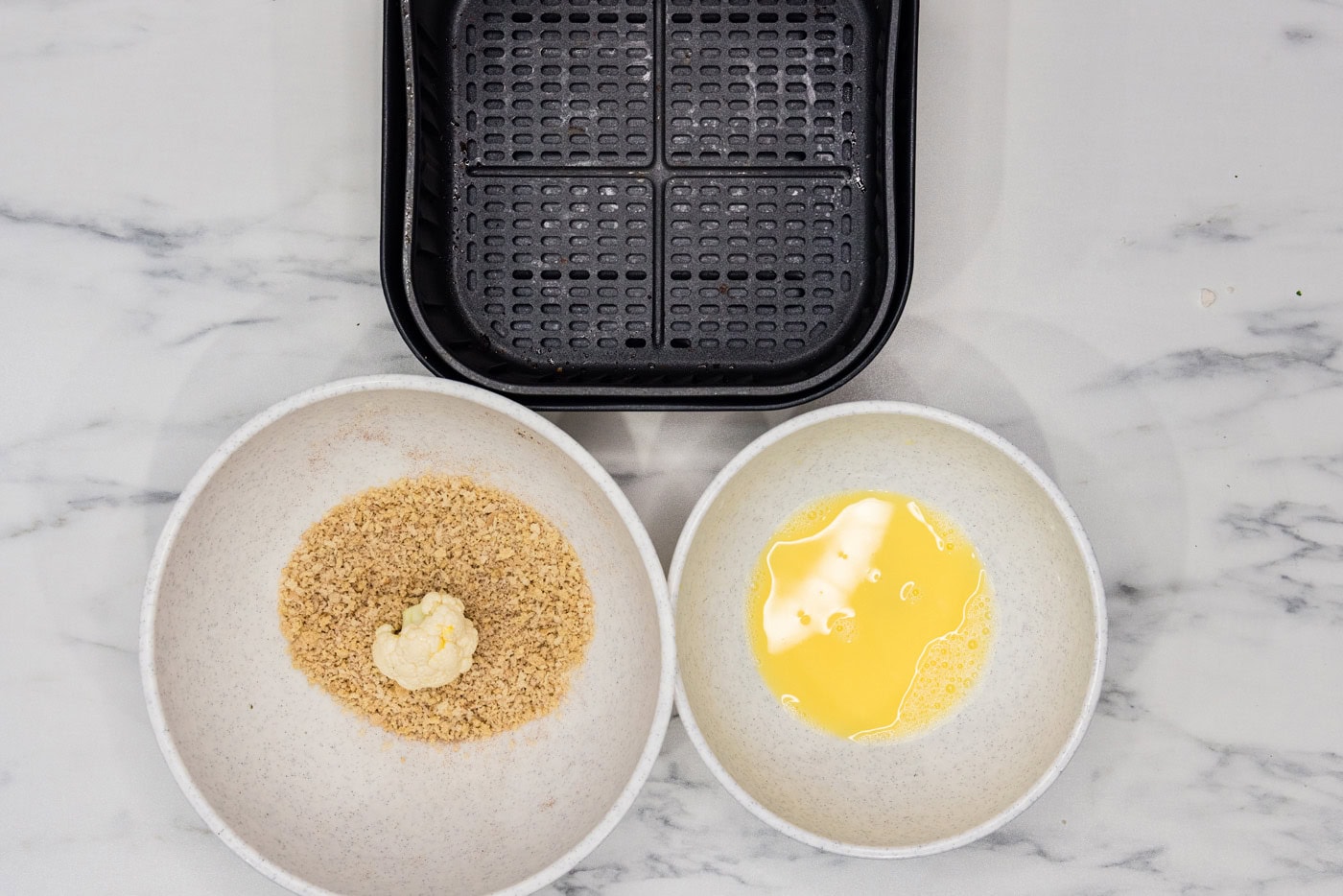 egg dredged cauliflower floret in a bowl of panko breadcrumbs