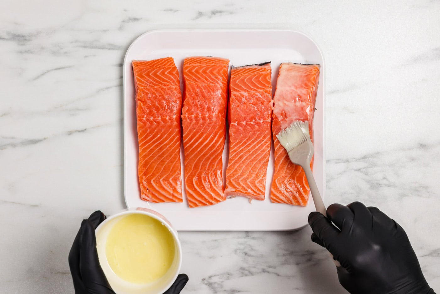 brushing lemon butter mixture over salmon filets