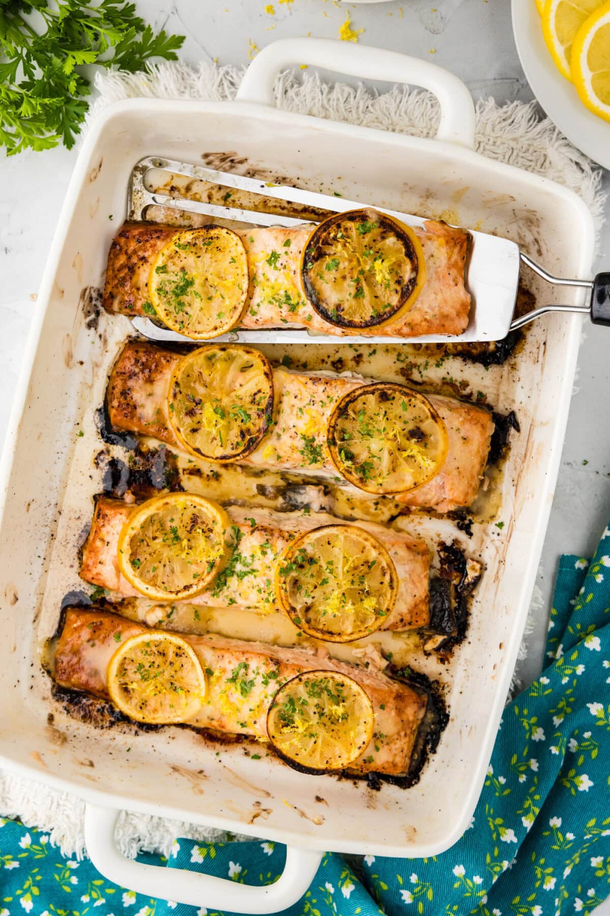 Baking dish of Baked Lemon Salmon with a filet being removed