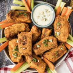 Platter of Buffalo Chicken Egg Rolls with carrots, celery and a bowl of blue cheese dressing