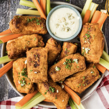 Platter of Buffalo Chicken Egg Rolls with carrots, celery and a bowl of blue cheese dressing