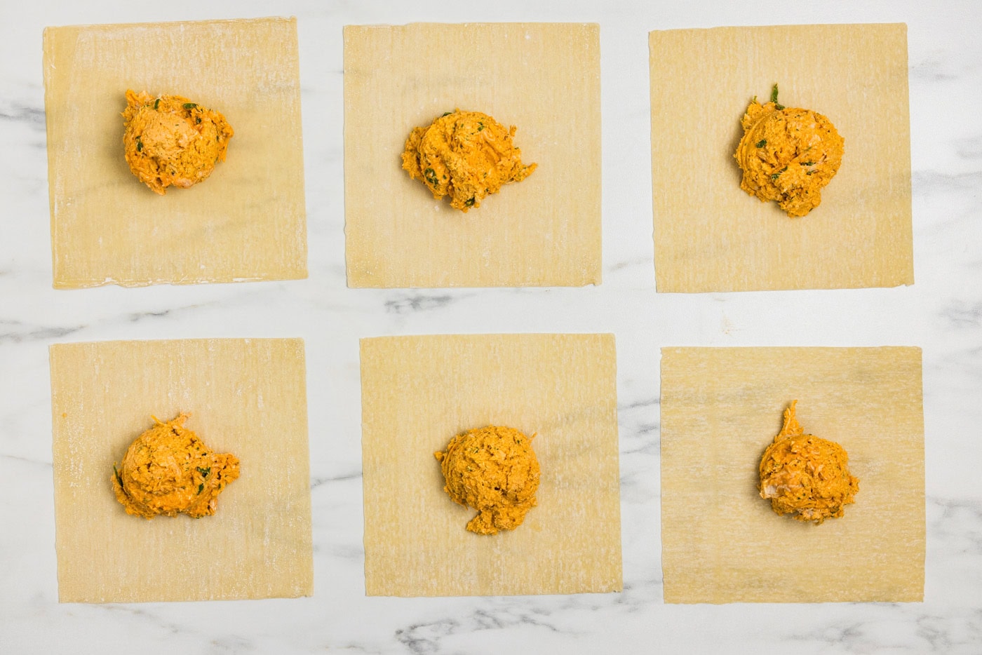 egg roll wrappers on a flat surface with buffalo chicken mixture on top