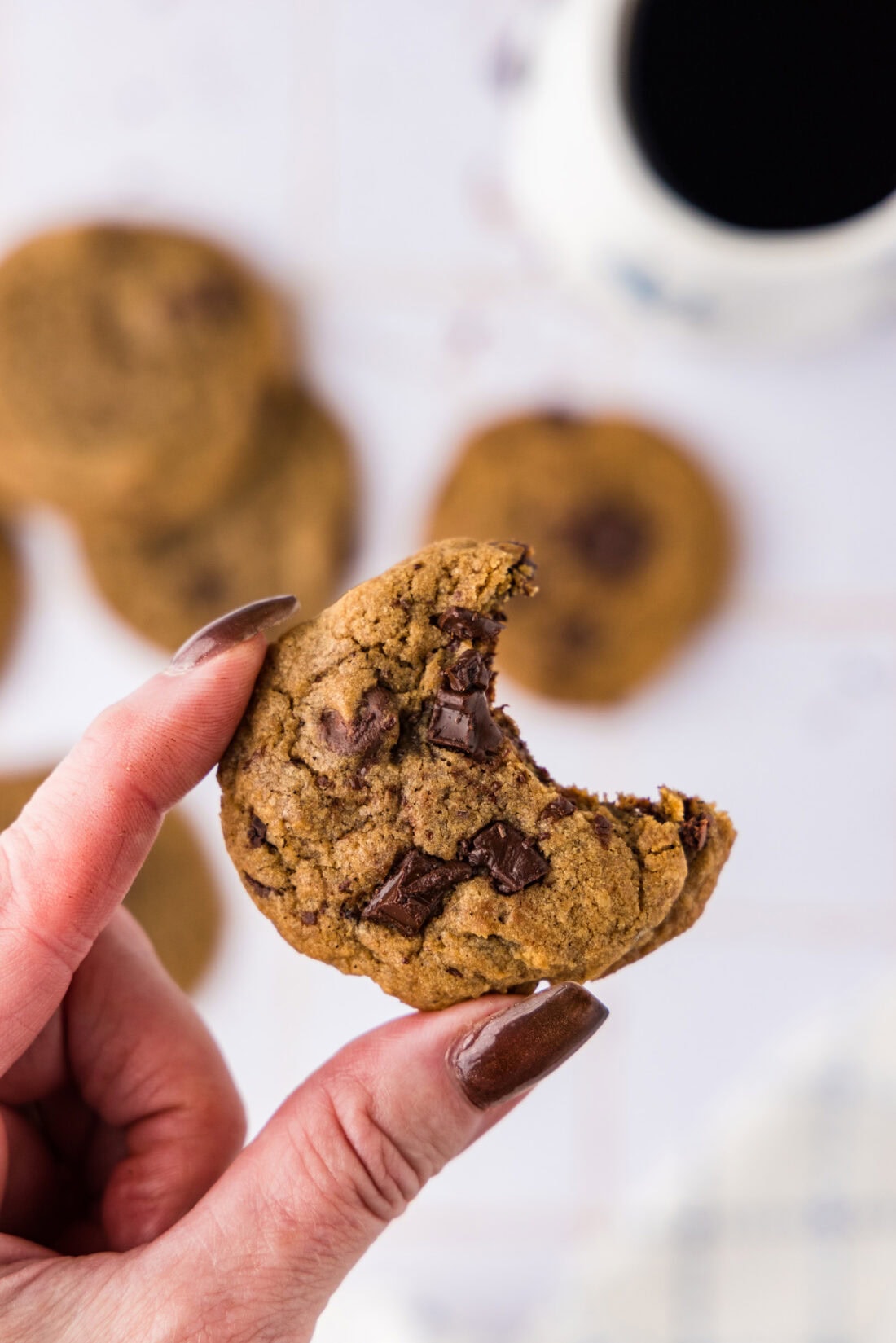 Hand holding a Chocolate Chip Espresso Cookie with a bite taken out of it