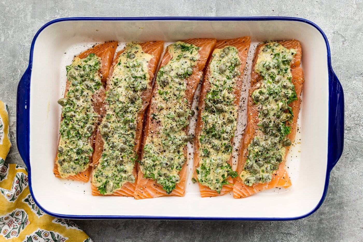 salmon filets in a baking dish topped with marinade and salt and pepper