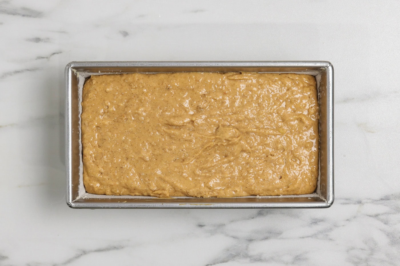 pumpkin banana bread batter in a floured loaf pan
