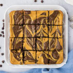 Close up photo of Pumpkin Cheesecake Brownies on a platter cut into squares