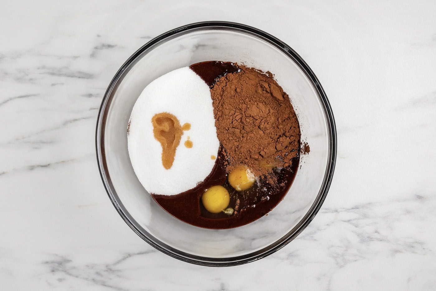 eggs, cocoa, sugar, and vanilla added to melted chocolate in a bowl