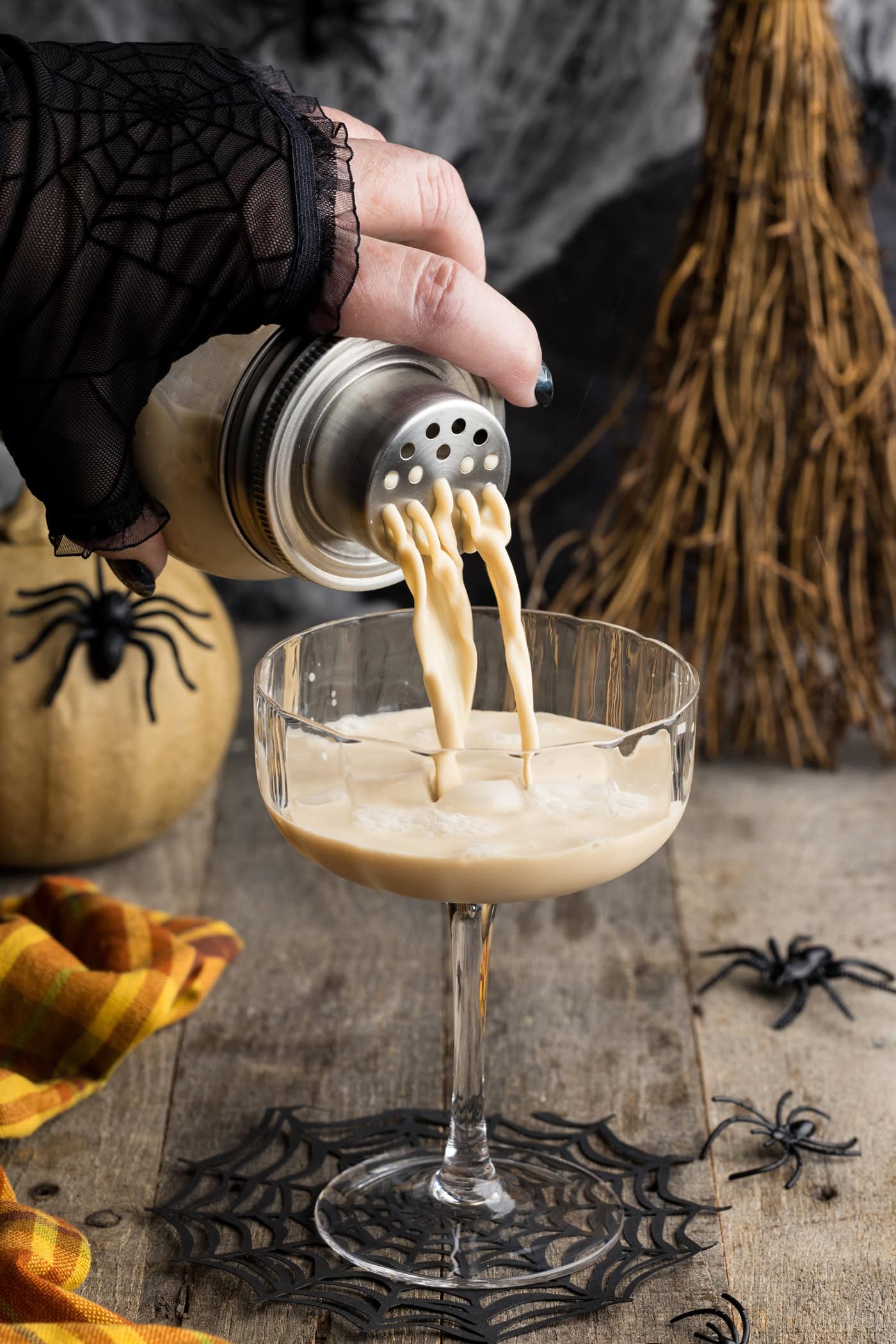 straining a White Russian cocktail into a coupe glass