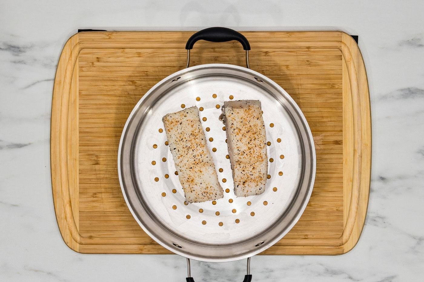 seasoned Chilean sea bass filets in a steamer basket