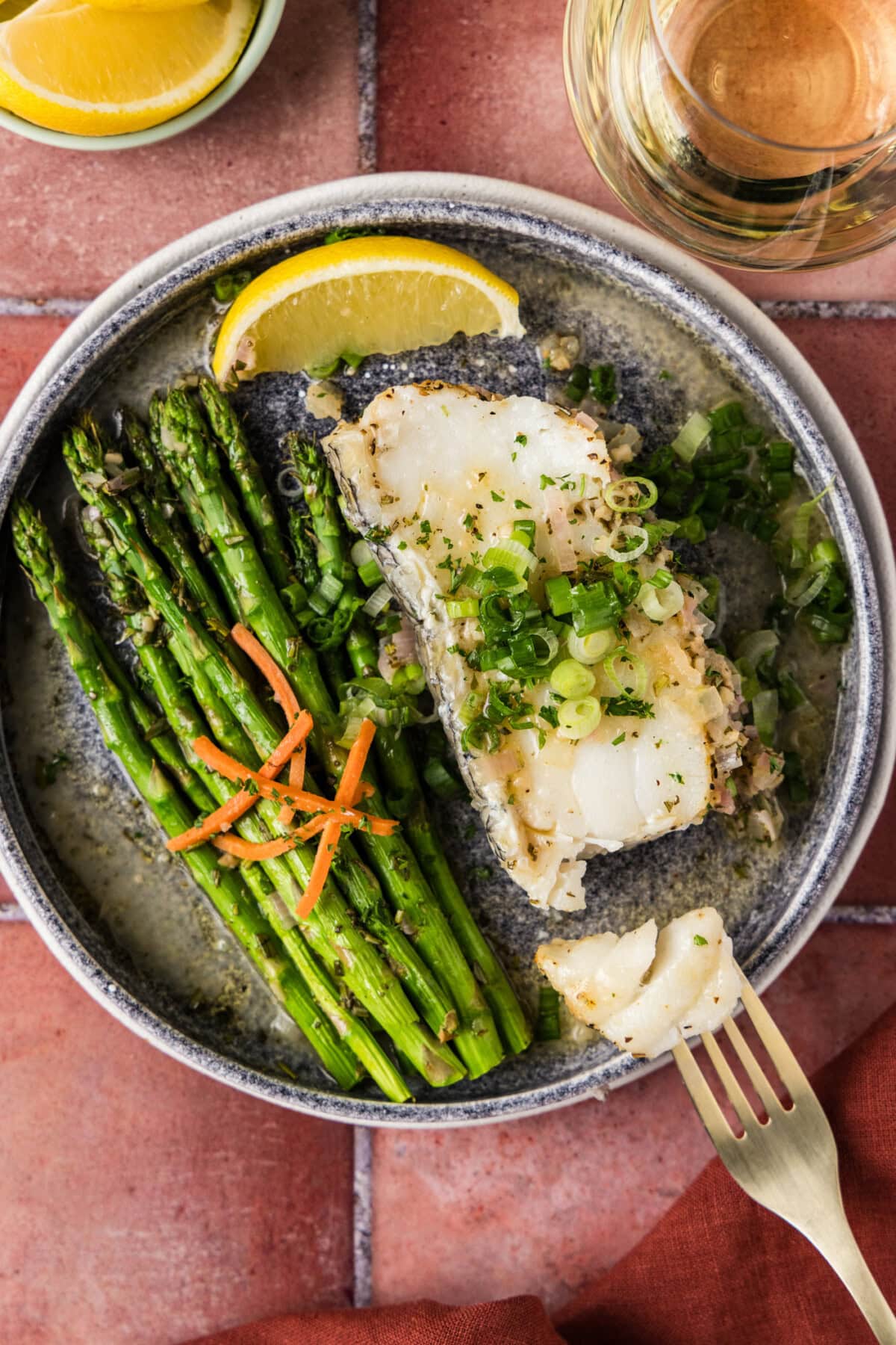 Steamed Chilean Sea Bass on a plate broken apart by a fork