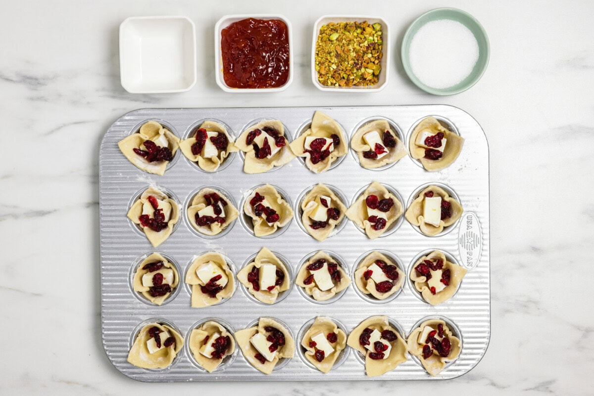 dried cranberries added to brie bites in a mini muffin pan