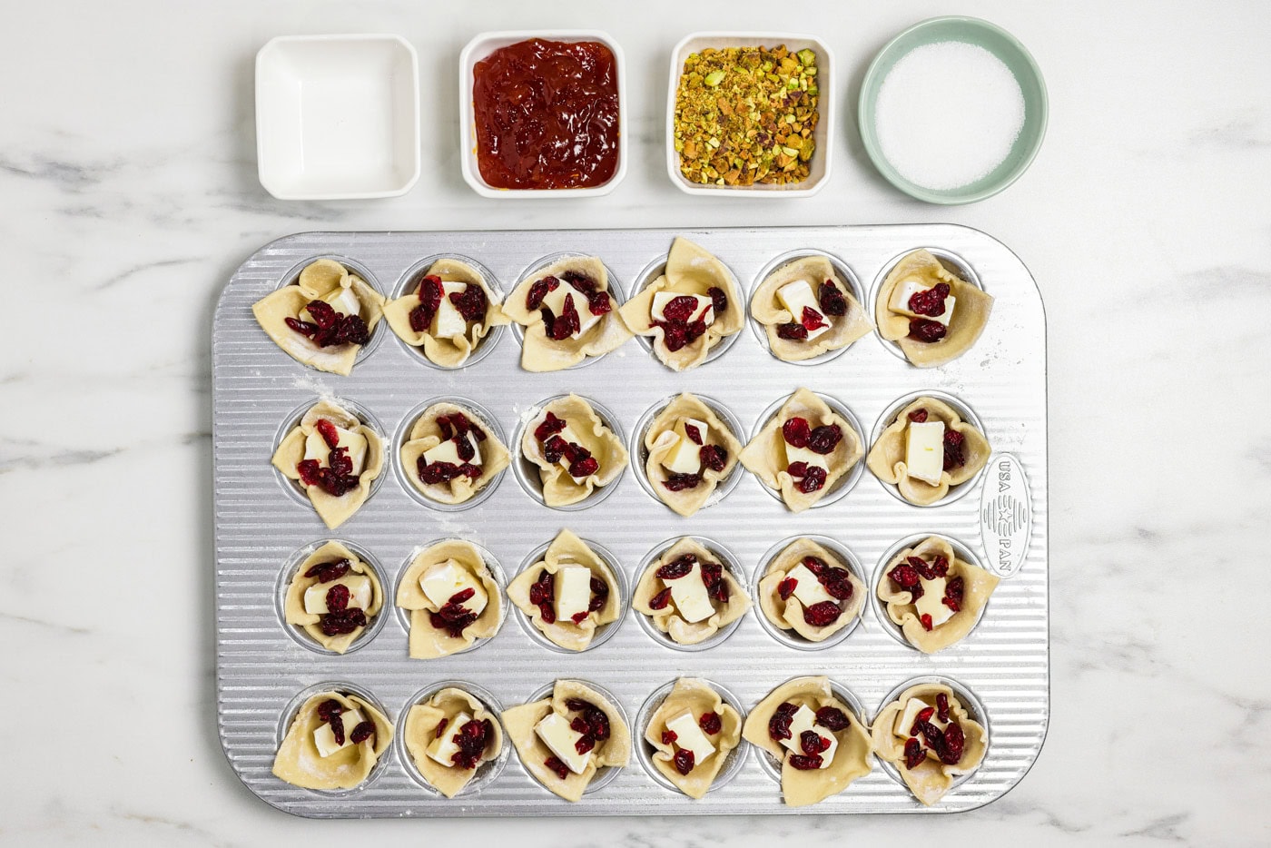 dried cranberries added to brie bites in a mini muffin pan