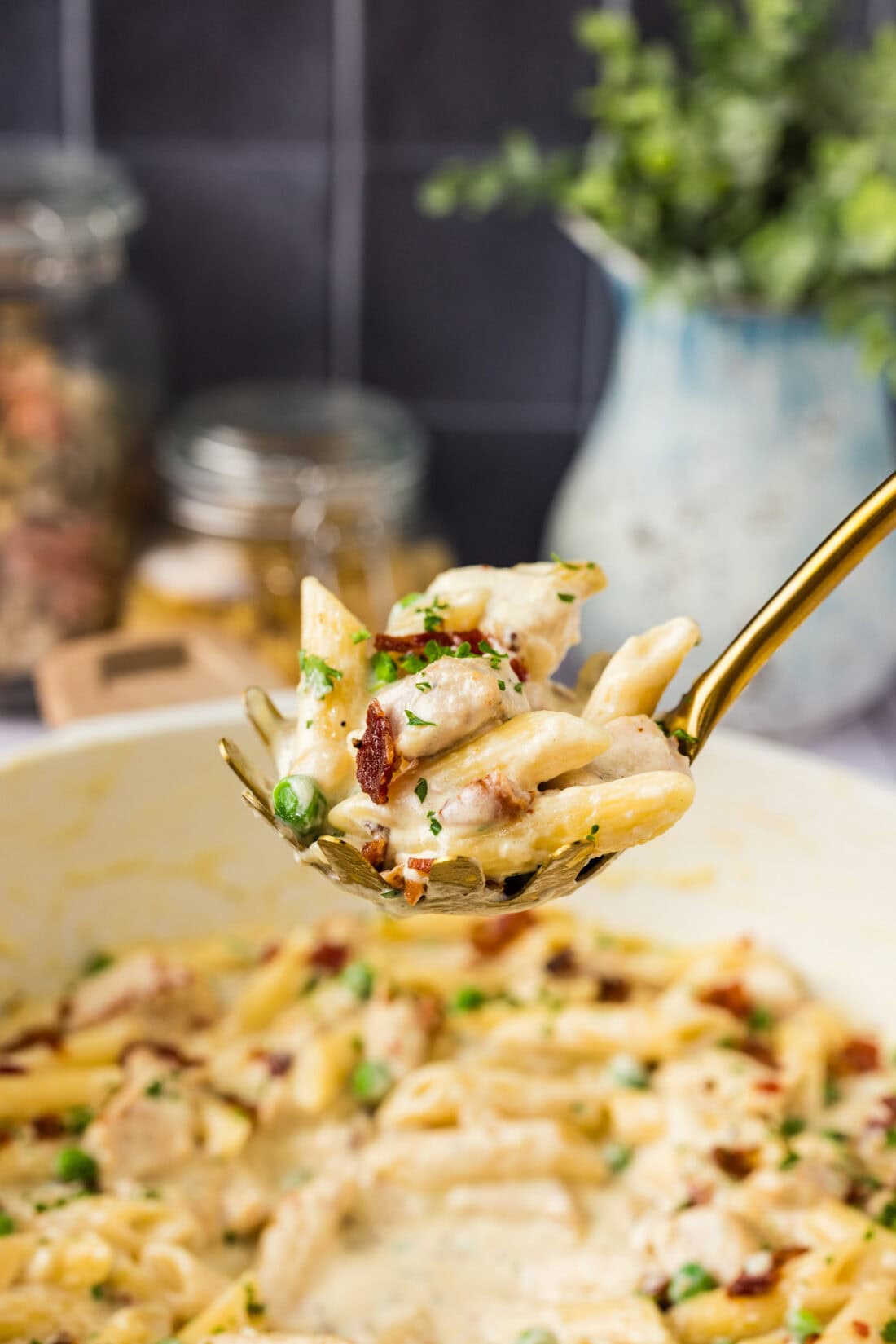 Spoonful of Chicken Carbonara held above a skillet of Chicken Carbonara