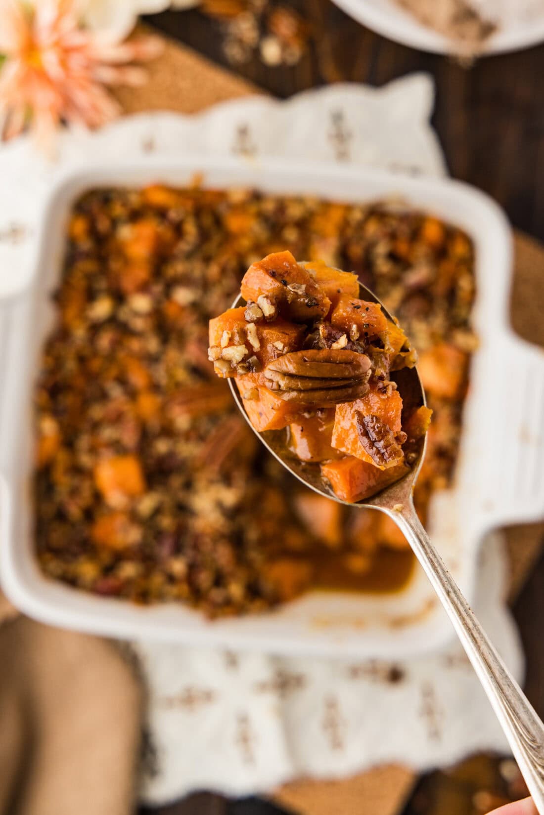 Spoonful of Kentucky Bourbon Sweet Potatoes held above a baking dish of Kentucky Bourbon Sweet Potatoes