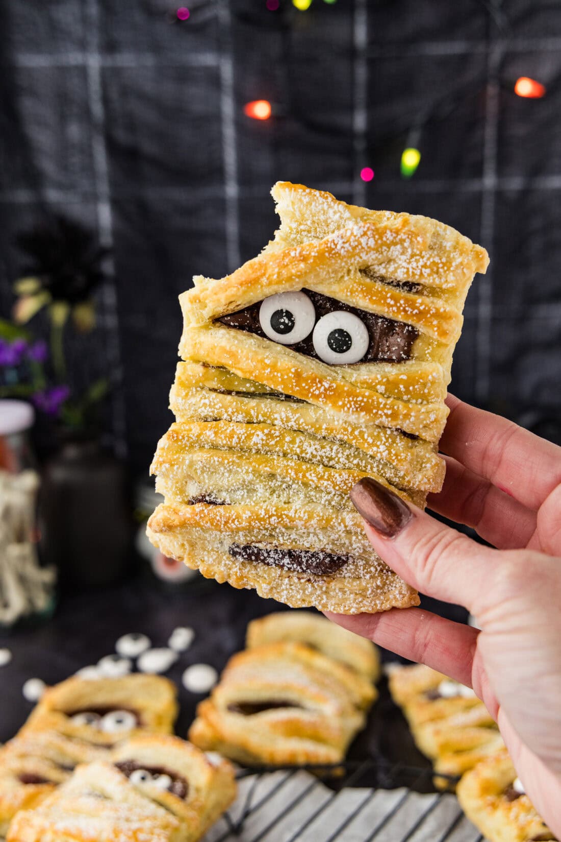 Hand holding a Mummy Hand Pie with a bite taken out