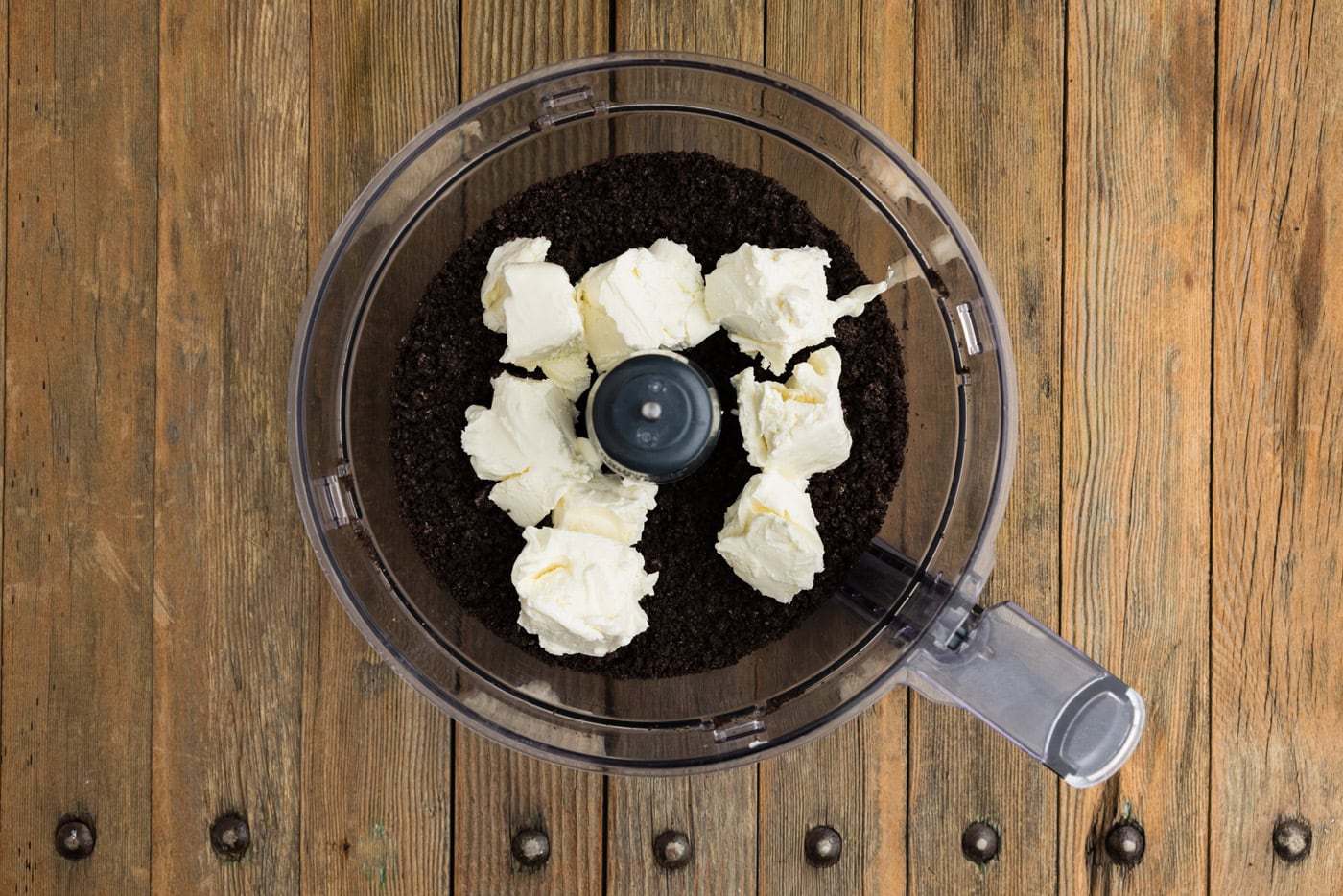 cubed cream cheese in a food processor bowl along with crumbled Oreos
