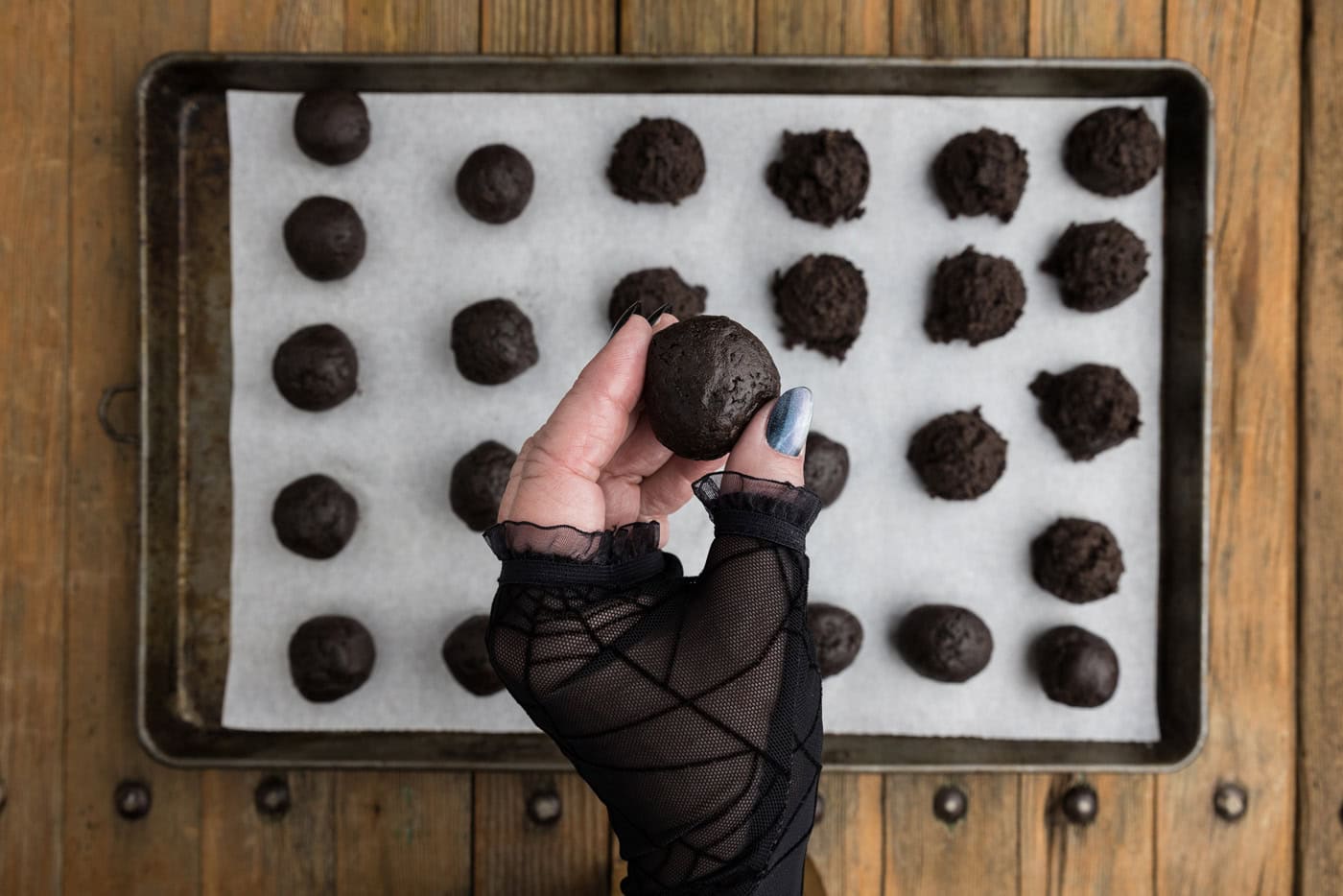 hand holding an Oreo truffle ball over a baking sheet