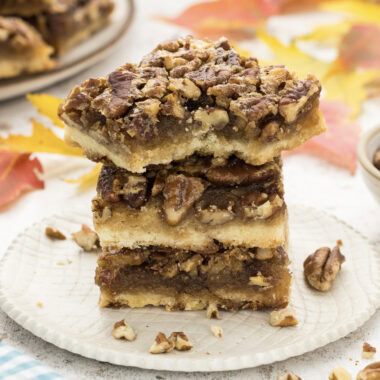 Close up photo of a stack of Pecan Pie Bars with a bite taken out of one