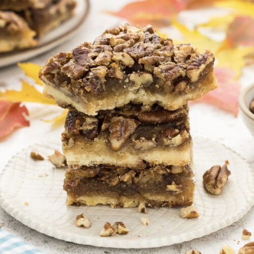 Close up photo of a stack of Pecan Pie Bars with a bite taken out of one