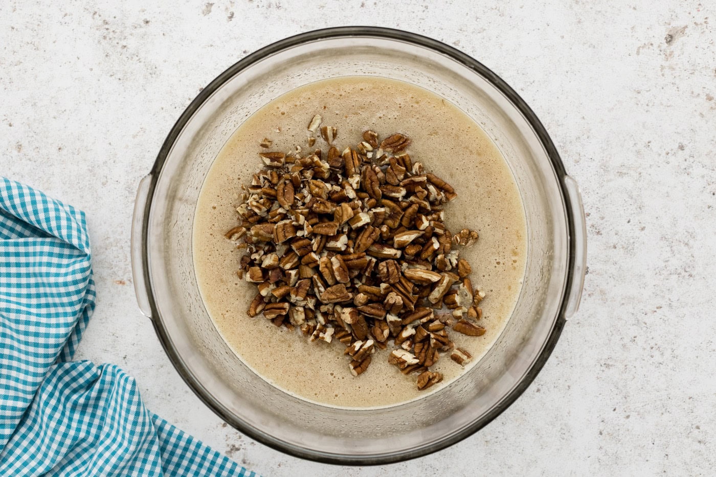 chopped pecans added to pecan pie filling in a mixing bowl