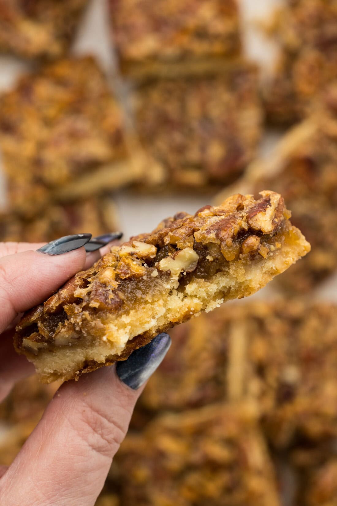 Hand holding a Pecan Pie Bar with a bite removed