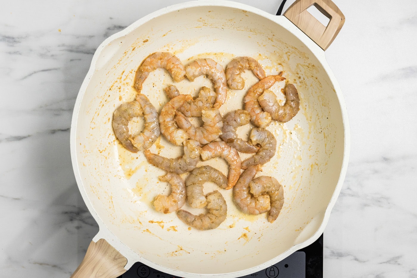 partially cooked shrimp in a skillet