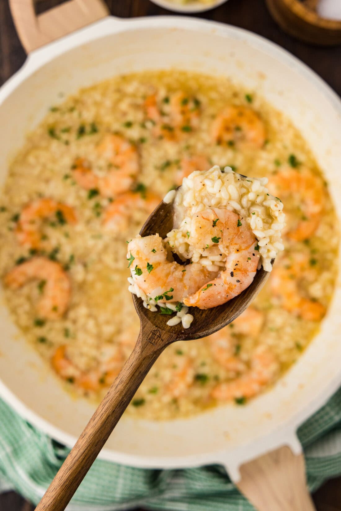 Spoonful of Shrimp Risotto held above a skillet of Shrimp Risotto