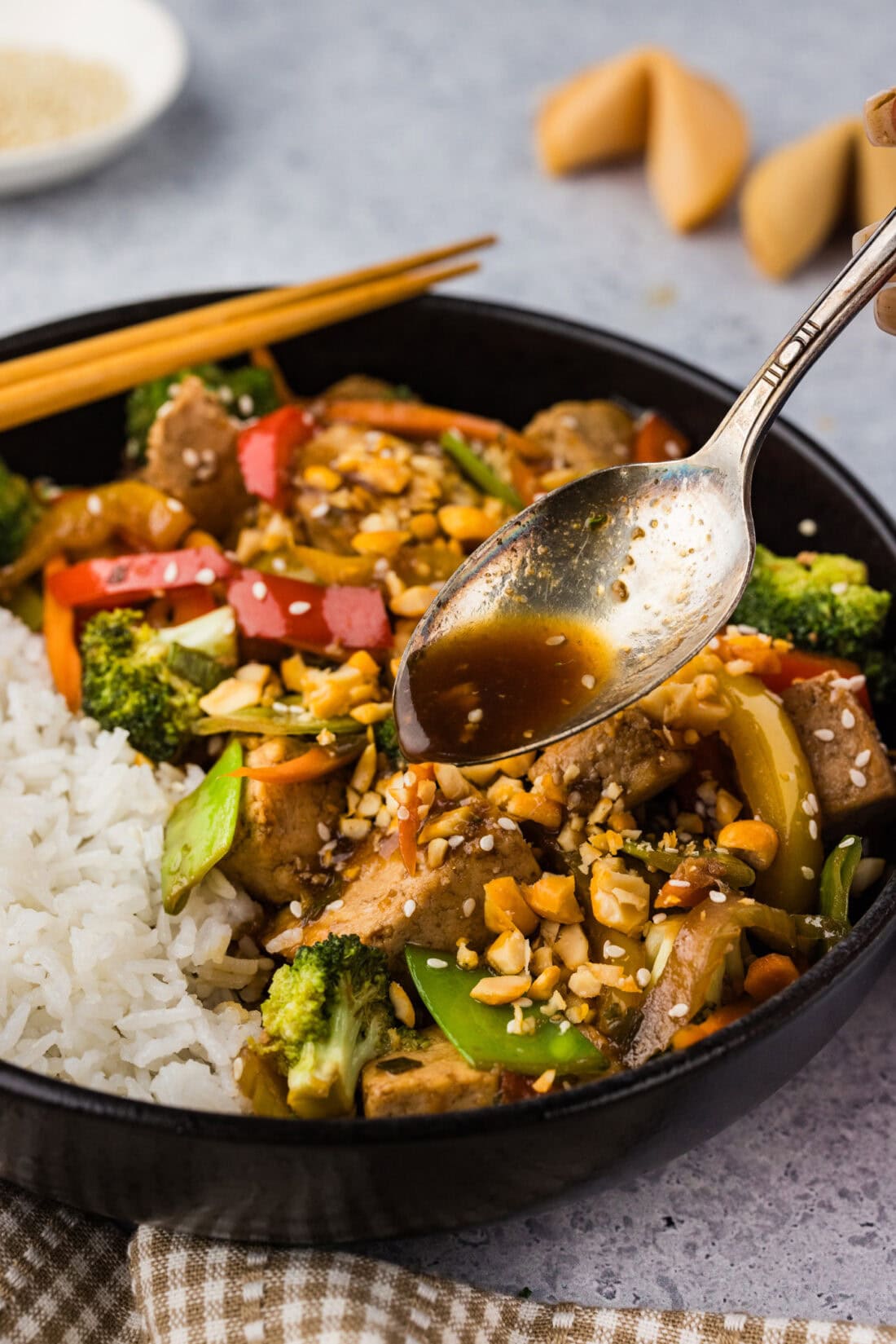 Spoon drizzling sauce over Tofu Stir Fry