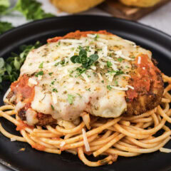 Close up photo of Veal Parmesan plated on top of spaghetti
