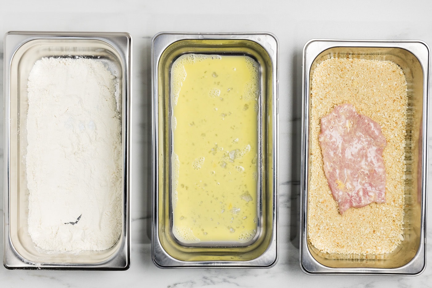 dredged veal cutlet in breading tray with panko bread crumbs