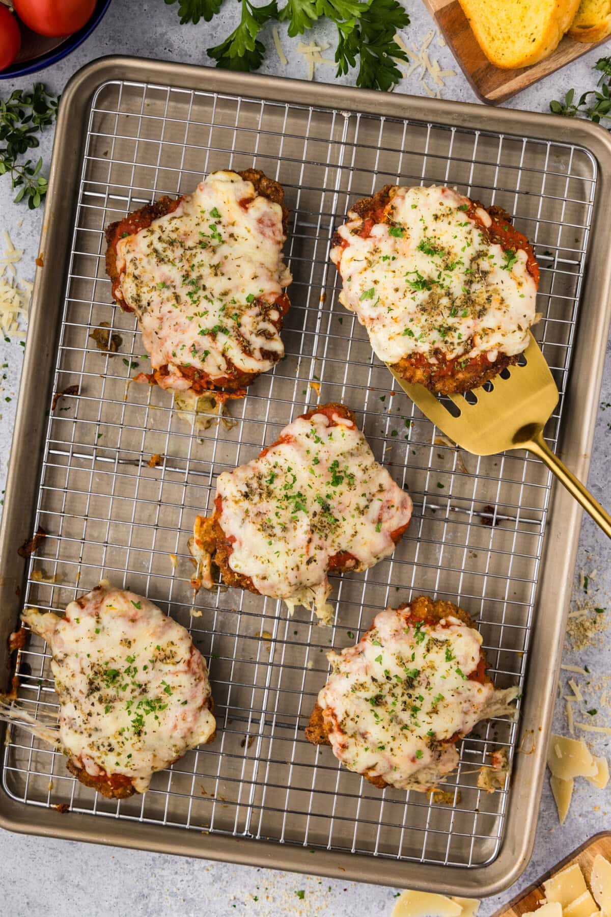 Veal Parmesan resting on a baking sheet with a spatula