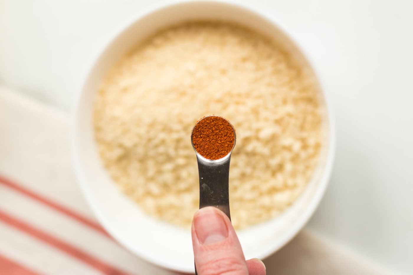 Paprika being added to a bowl of breadcrumbs