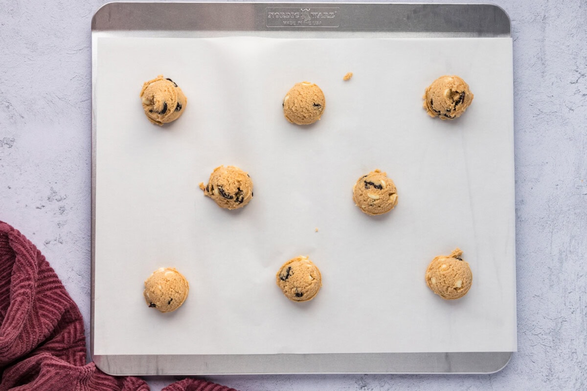 cherry white chocolate chip cookie dough balls on parchment lined baking sheet
