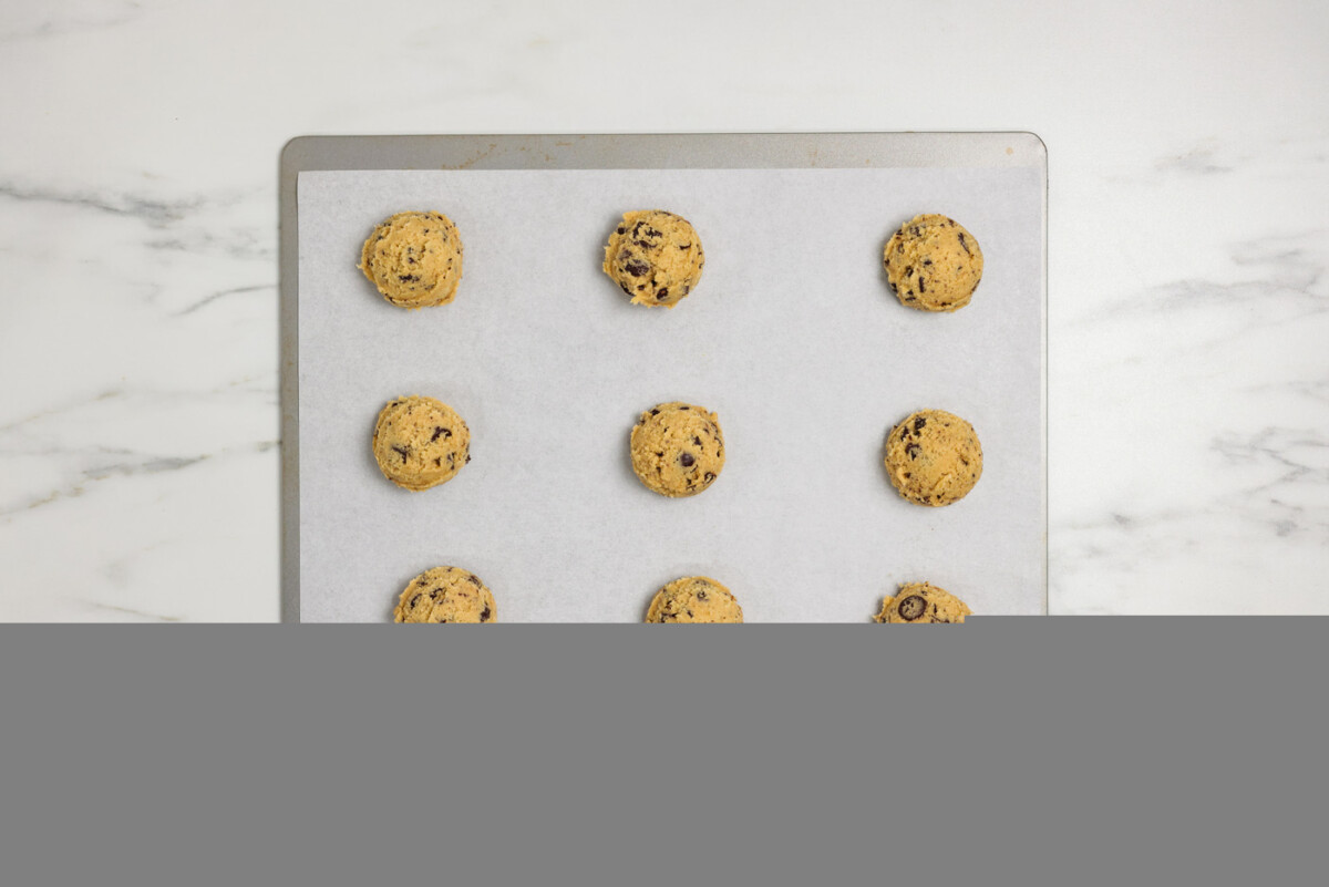 chocolate chip cookie dough balls on a parchment lined baking sheet