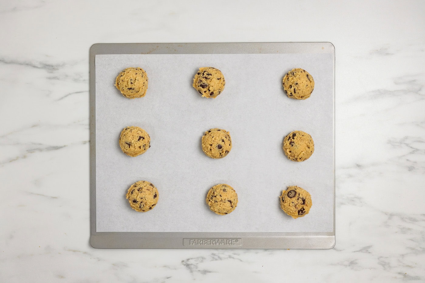chocolate chip cookie dough balls on a parchment lined baking sheet