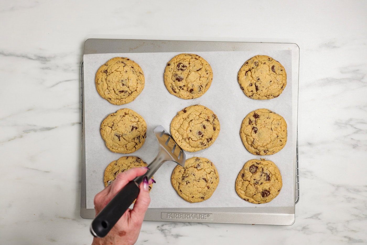 rounding the edges of baked cookies with a spatula