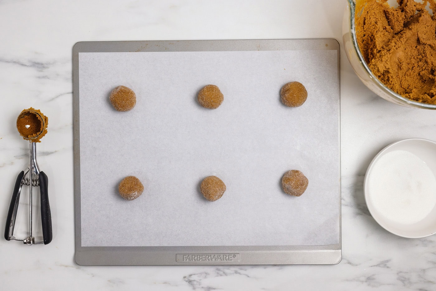 gingersnap cookie dough balls coated in sugar onn a baking sheet