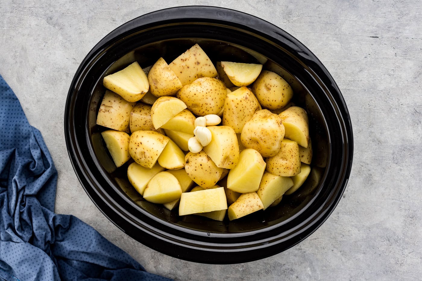 garlic added to crockpot with cubed yukon gold potatoes and broth