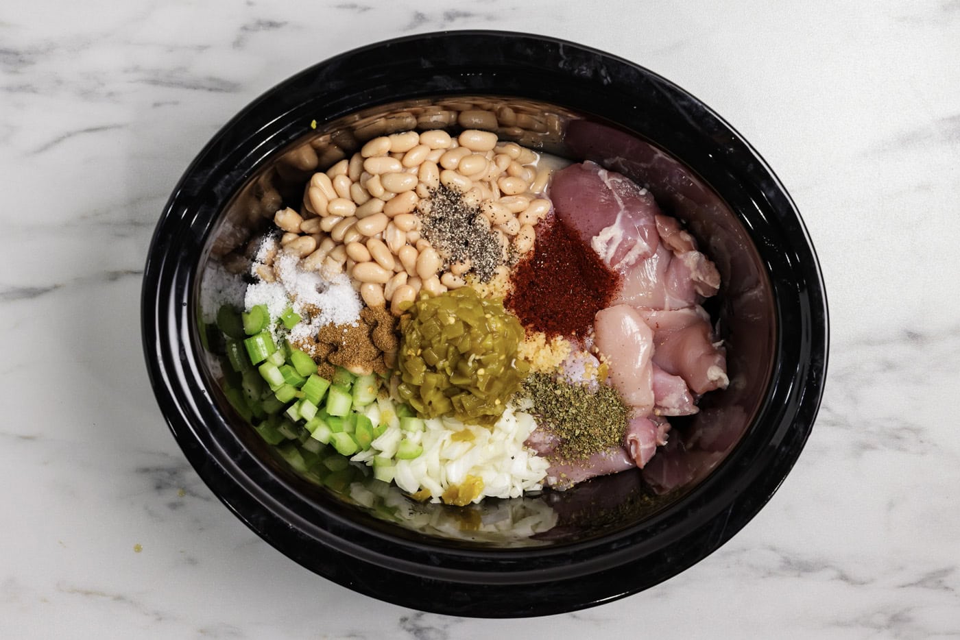 white chicken chili ingredients in the crock of a slow cooker