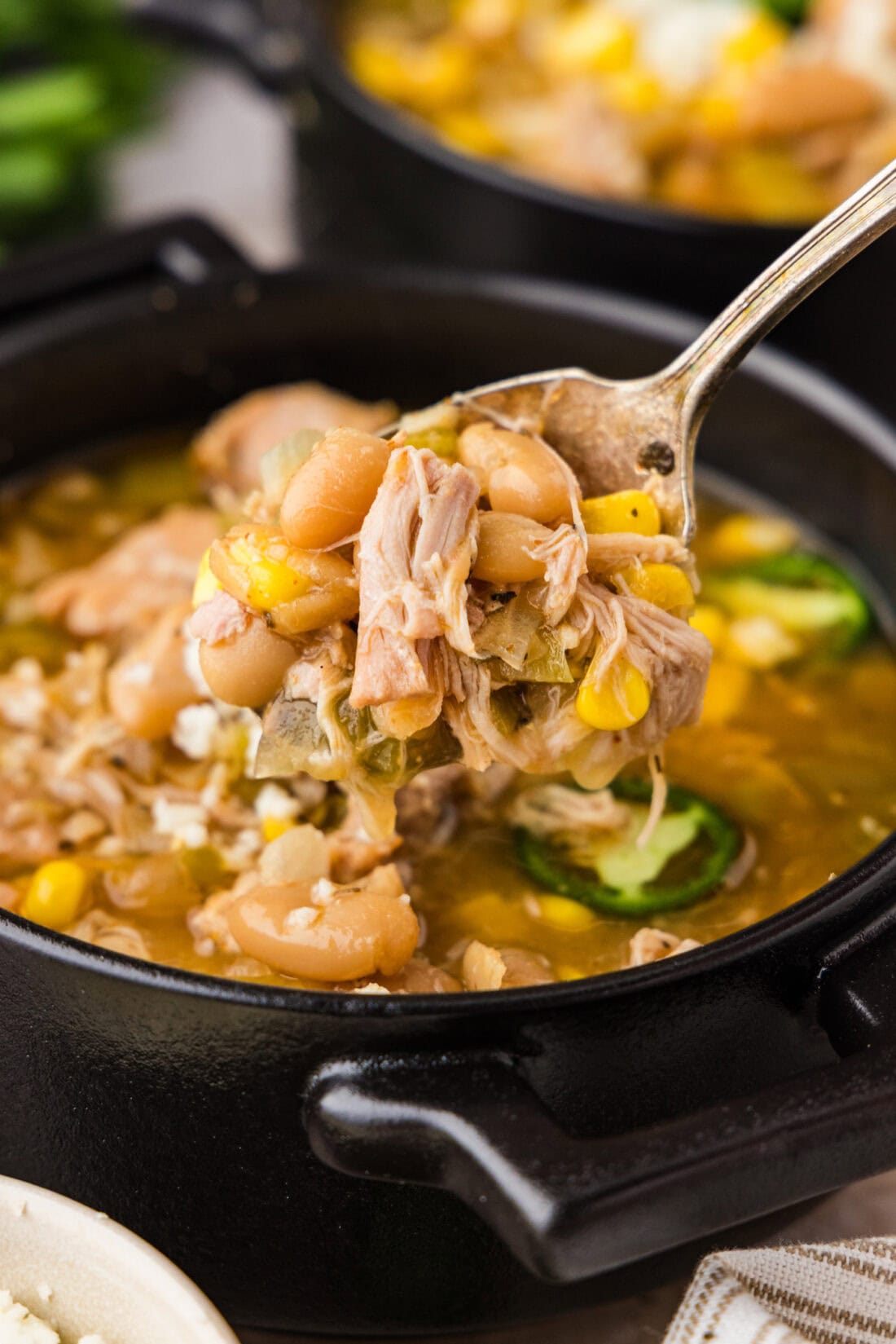 Spoon lifting up Crockpot White Chicken Chili from a bowl