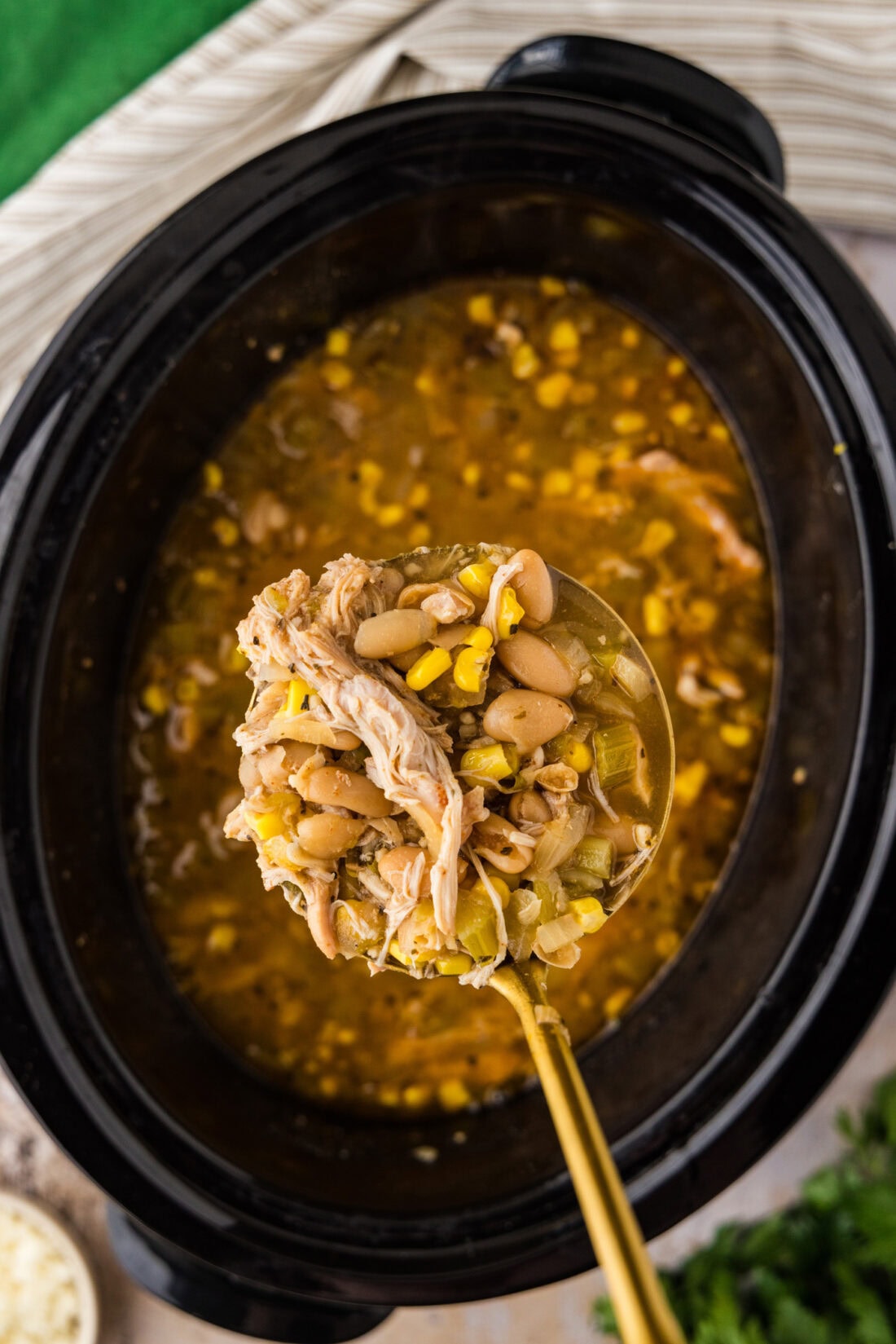 Spoon of Crockpot White Chicken Chili held above a Crockpot of Crockpot White Chicken Chili