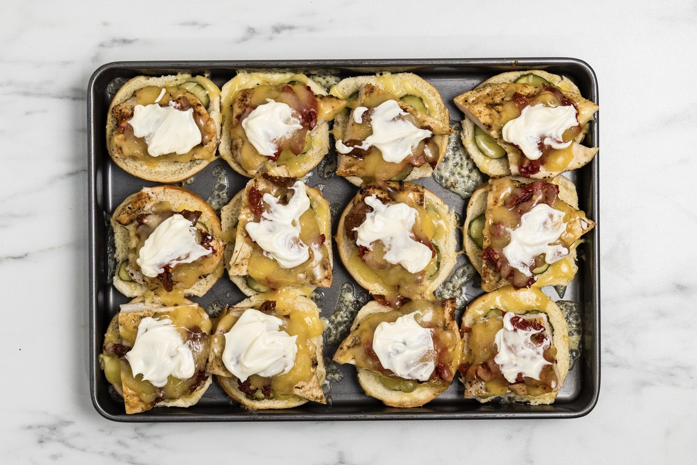 mayo dolloped on top of layered gouda chicken slider ingredients