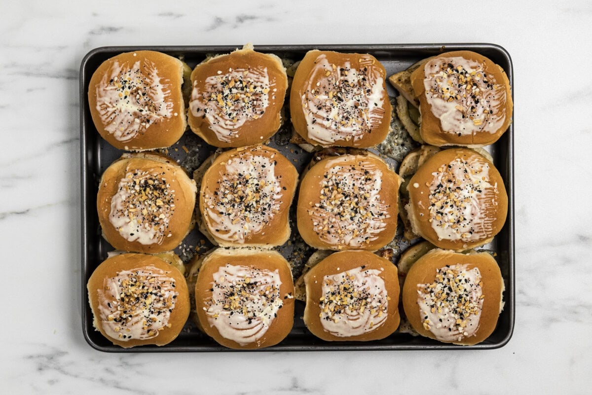 gouda chicken sliders on a baking sheet brushed with butter and sprinkled with everything bagel seasoning