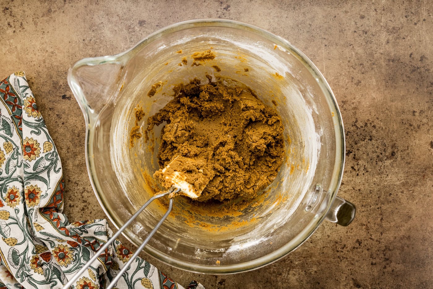 molasses spice cookie dough in a stand mixer bowl with a rubber spatula